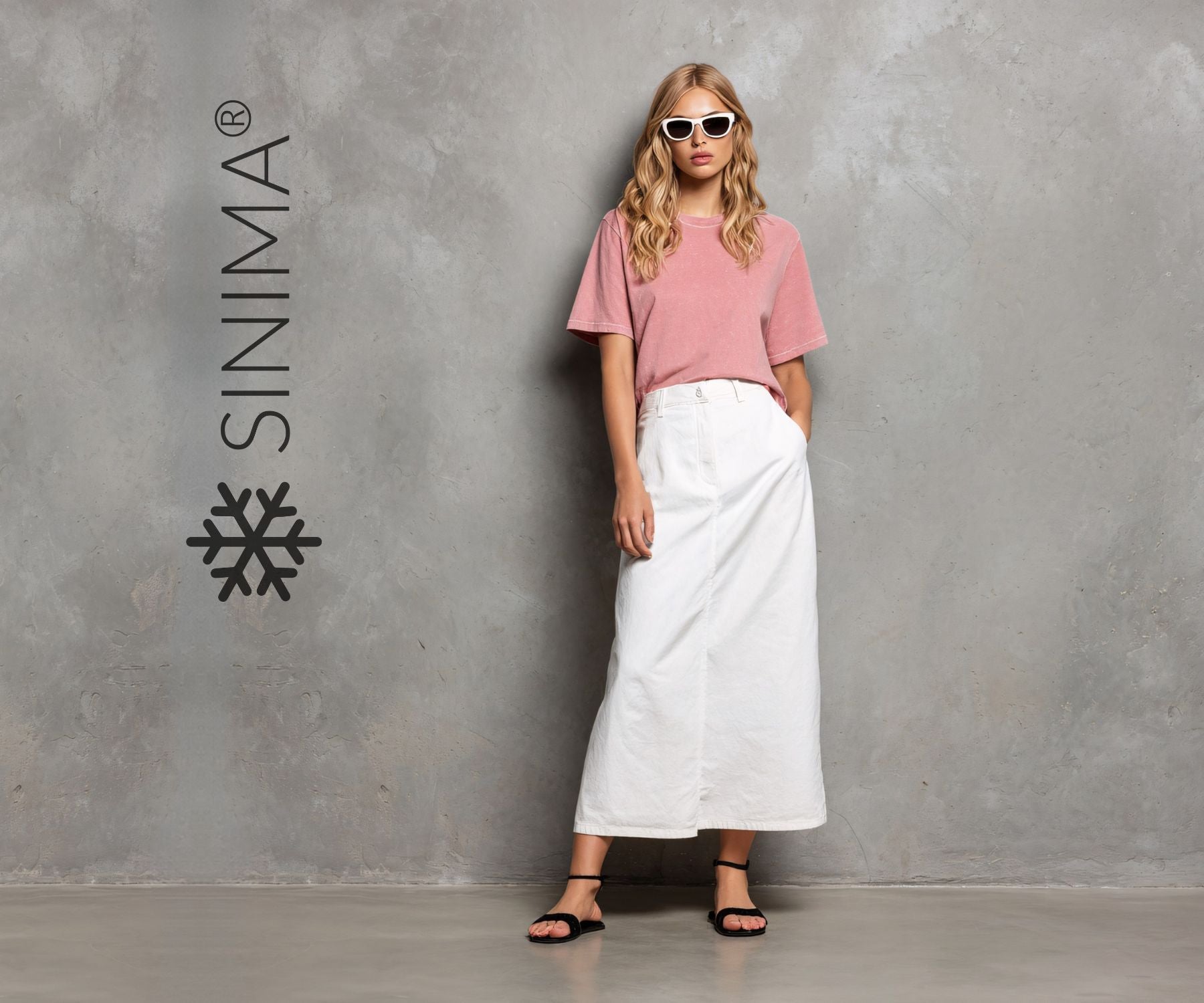 Woman in pink top and white skirt standing against a gray wall with SINIMA logo.